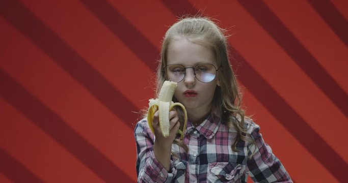 Child eating banana and complaining to camera