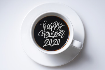 White cup of black coffee and happy new year 2020 great hand latter on white