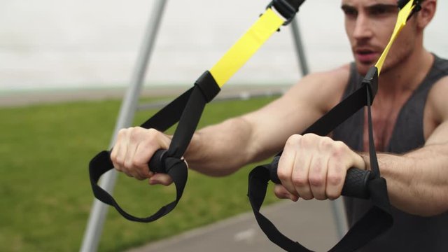 Closeup man working out with trx fitness rope. Guy training with suspension rope