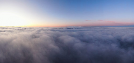 Naklejka na ściany i meble Aerial Panoramic View of Pacific Ocean Coast Covered in Fog and Clouds during a colorful sunny sunrise. Taken in Vancouver Island, BC, Canada near Tofino and Ucluelet.