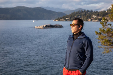 Portrait of an Adventurous Latin Man outside in nature during a cloudy and sunny sunset. Taken in Lighthouse Park, Horseshoe Bay, West Vancouver, BC, Canada.