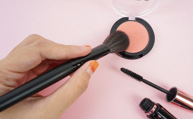 A hand pointing the brush on blusher powder.
