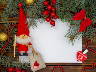 On a wooden background, a white sheet of paper around it Christmas decor.