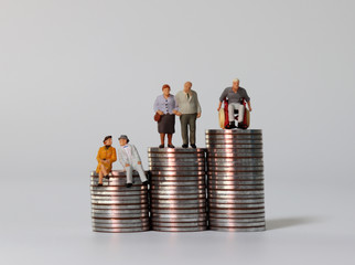 Old age miniature people on pile of coins. 