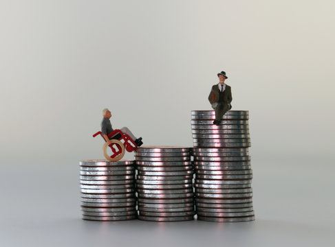 Miniature people in piles of coins of different heights. The concept of employment inequality for the disabled.