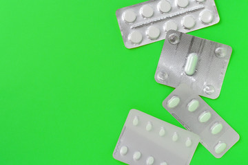 Blisters with tablets on a bright green background. Top view, copy space. Pharmacy concept
