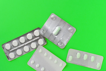 Blisters with tablets on a bright green background. Top view, copy space. Pharmacy concept