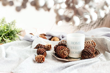 Candle with the inscription on a silver plate with cones in the Christmas decor. Home decoration. 