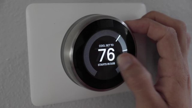 Man Adjusting Smart Thermostat Gadget At Home