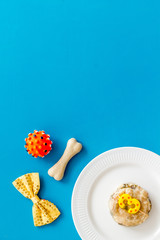 Birthday party for puppy concept. Dog feed, candle, bone, bow-tie on blue background top-down copy space
