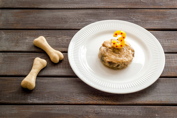 Birthday treat for puppy concept. Dog feed, candle in shape of number three, bones on dark wooden background