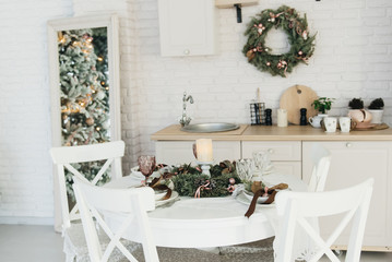 Festive table setting among winter decorations. Kitchen decor. The concept of a Christmas or thanksgiving family dinner.