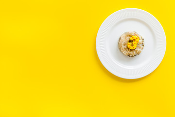 Cat's birthday concept. Pet feed with festive candle in shape of three on yellow background top-down copy space