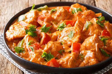 Authentic african chicken mafe in peanut sauce, with tomatoes, peppers and coconut milk close-up in a plate on the table. horizontal