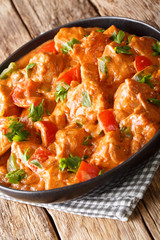 West African chicken mafe in peanut sauce close-up in a plate on the table. vertical