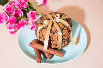 Fresh baked oatmeal cookies on a blue plate on a peach background and a bouquet of roses. Delicious healthy culinary sweet dessert for a romantic festive breakfast, food