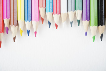 Rainbow colour pencils on the white paper over the white background