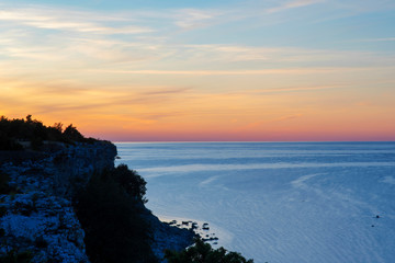 Fototapeta na wymiar Summer Sunset Over Calm Ocean With Limestone Coastal Landscape In the Foreground At Halshuk On The Island Of Gotland, Sweden
