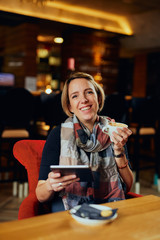 Beautiful Caucasian woman with coffee looking at her tablet	