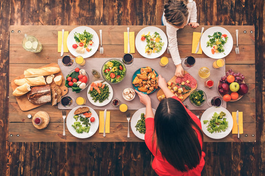 Young Woman And Her Daughter Putting Food On Table