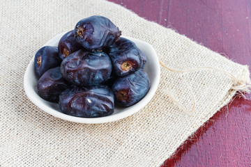 Dried dates in ceramic plate over piece of sack
