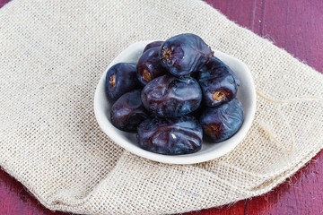 Dried dates in ceramic plate over piece of sack