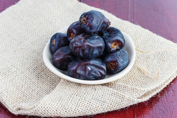 Dried dates in ceramic plate over piece of sack