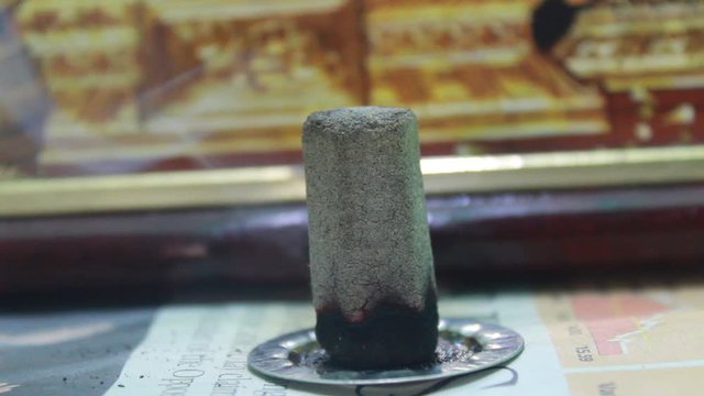 Close up shot of dhoop batti / incense stick burning with some smoke on the pooja room and some light passing through the dhoop batti