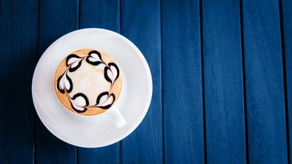 Cup of coffee or chai tea with latte art on blue wooden table. Leasure time concept. Pastel colors. Horizontal