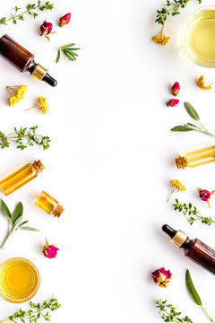 Natural wellness. Essential oils near herbs and leaves on white background top view pattern frame copy space