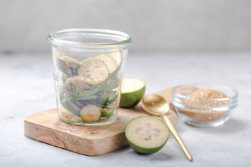 Ground green feijoa with sugar on a wooden cutting Board in a glass jar. Gray background. Top view. Healthy eating ingredients concept