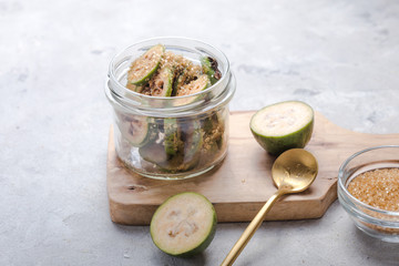 Ground green feijoa with sugar on a wooden cutting Board in a glass jar. Gray background. Top view. Healthy eating ingredients concept