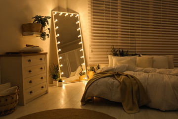 Stylish mirror with light bulbs in dark bedroom. Interior design