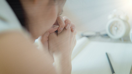 Female Praying With her Hands Folded On The Bible