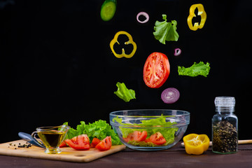 ingredients for vegetable salad are flying in a plate on a black background
