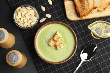 Delicious broccoli cream soup with croutons served on black table, flat lay