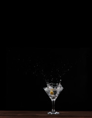 in a Martini glass falls olive, splashes of beautifully flying on black background