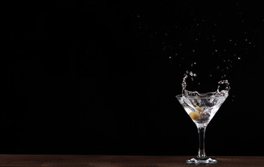 in a Martini glass falls olive, splashes of beautifully flying on black background