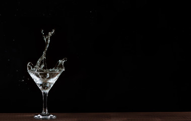 in a Martini glass falls olive, splashes of beautifully flying on black background