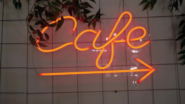 A neon sign that says cafe hanging on the wall in the coffee shop. 