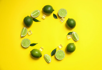 Flat lay composition with fresh juicy limes and ice cubes on yellow background. Space for text