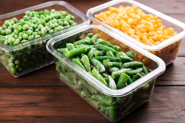 Different tasty frozen vegetables on wooden table
