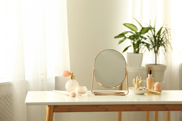 Mirror and makeup products on white table indoors