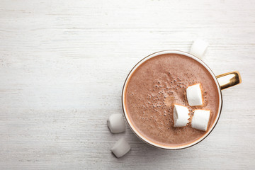 Cup of delicious hot cocoa with marshmallows on white wooden table, flat lay. Space for text