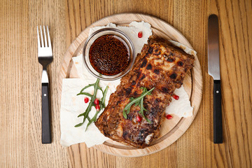 Delicious grilled ribs served on wooden table, flat lay