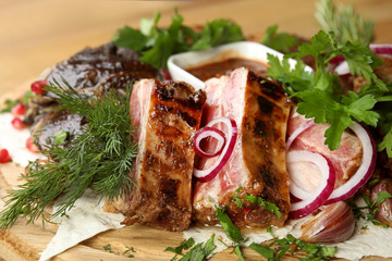Delicious roasted meat with herbal on wooden board, closeup