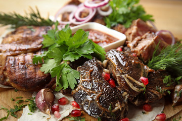 Delicious roasted meat with herbal on wooden board, closeup