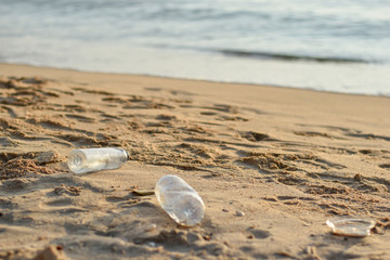 Plastic bottles on the brown sand near the beach, beach waste, marine pollution.
