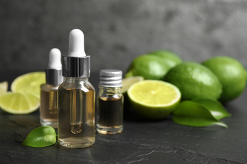 Lime essential oil and cut citrus fruits on black table