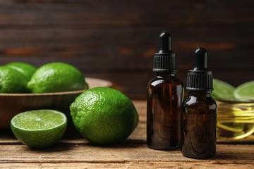 Lime essential oil and cut citrus fruits on wooden table